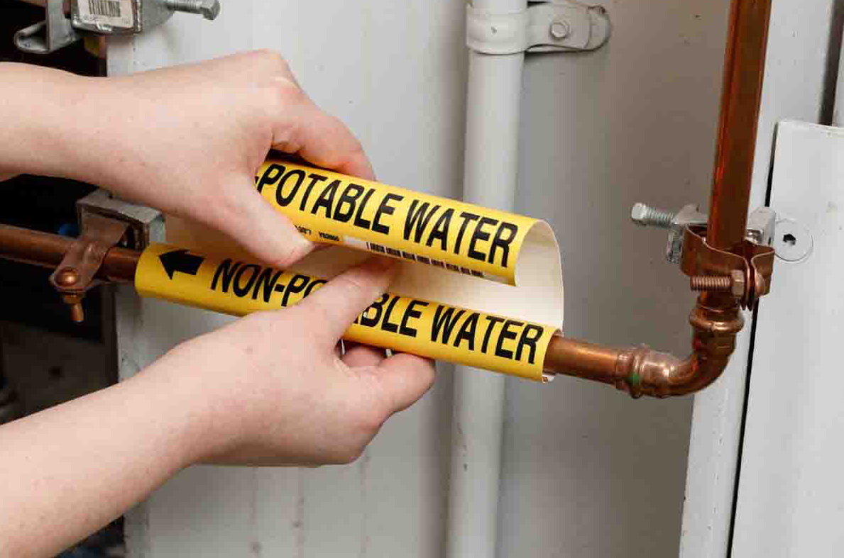 Close-up of someone applying a yellow Brady snap-on pipe marker